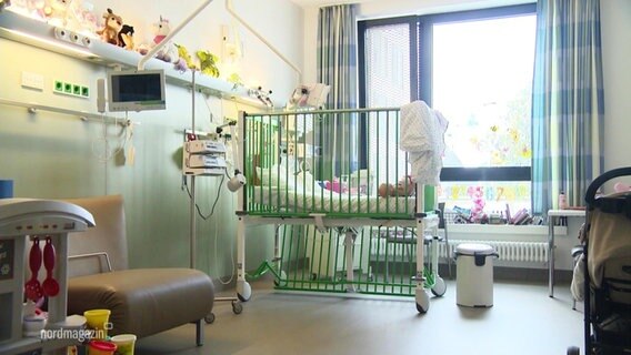 Ein Kinderbett steht in einem Krankenzimmer.  