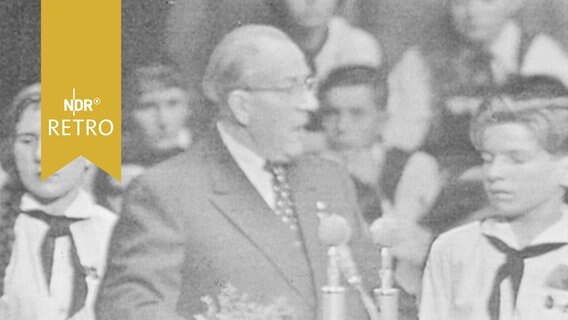 Otto Grotewohl zwischen eher gelangweilt guckenden Jungpionieren bei einer Rede (1960)  