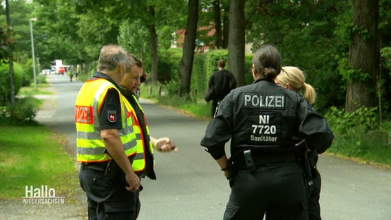 Polizeibeamte stehen an einer Straße © Screenshot 