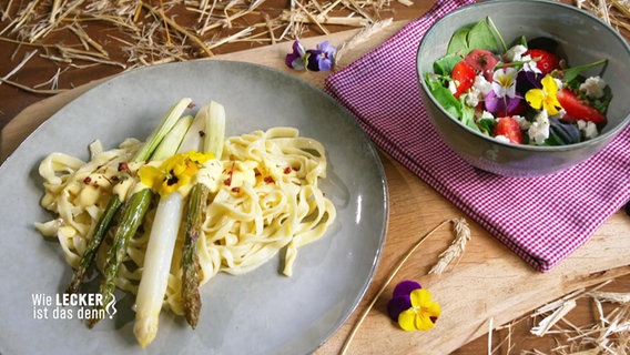 Grüner und weißer Spargel auf Nudeln. Daneben ein Salat mit Blumen. © Screenshot 
