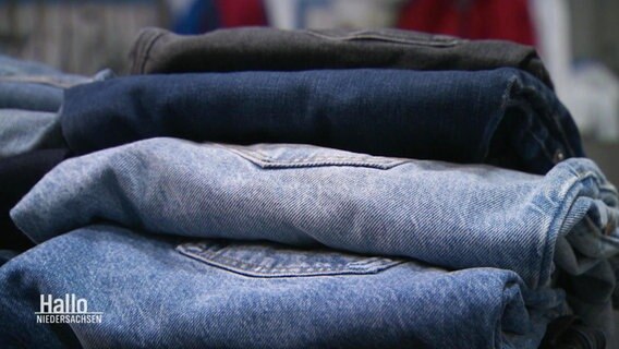 Ein Stapel Jeans in verschiedenen Blautönen liegt auf einem Tisch. © Screenshot 