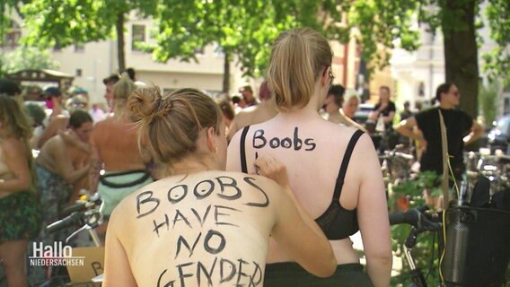 Bei einer Demo schreibt eine Frau einer anderen "Boobs have no gender" auf den Rücken. © Screenshot 