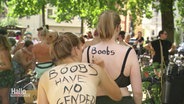 Bei einer Demo schreibt eine Frau einer anderen "Boobs have no gender" auf den Rücken. © Screenshot 