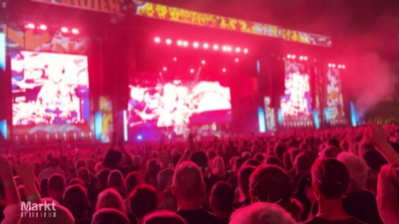 Viele Zuschauer stehen vor einer rot beleuchteten Bühne © Screenshot 