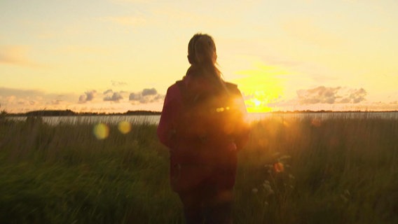 Eine Frau betrachtet einen Sonnenuntergang am Meer. © Screenshot 