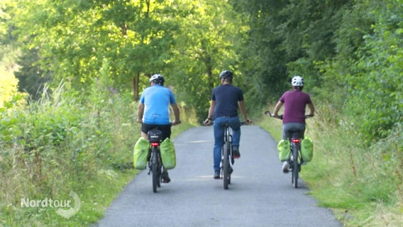 Drei Fahrradfahrer fahren nebeneinander auf einem Wanderweg. © Screenshot 