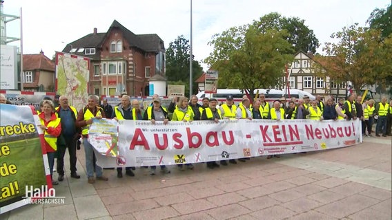 Protestierende halten ein Banner mit der Aufschrift: Ausbau - kein Neubau. © Screenshot 