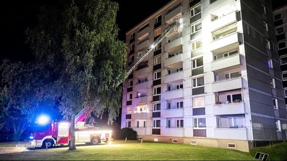 Ein Feuerwehreinsatzfahrzeug hat die Drehleiter ausgefahren und rettet Personen aus den oberen Stockwerken eines hohen Wohnhauses. © Screenshot 