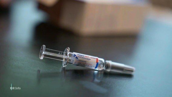 Eine Spritze mit Grippeimpfstoff liegt auf einem Tisch. © Screenshot 