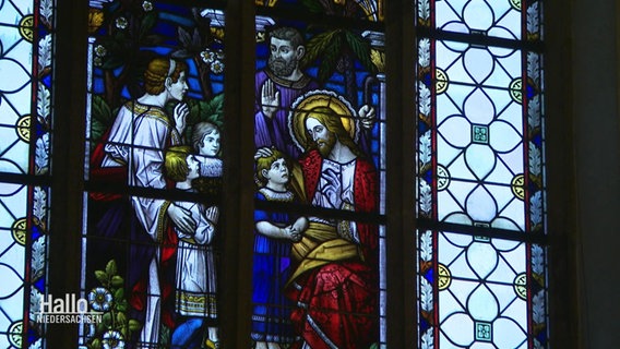 Ein buntes Kirchenfenster mit christlicher Symbolik. © Screenshot 
