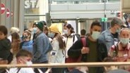 Menschen mit Schutzmaske in einer Einkaufspassage. © Screenshot 