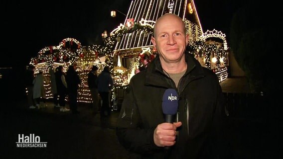 NDR Reporter Sven Borchart steht vor einem hell erleuchteten und weihnachtlich geschmücktem Haus. © Screenshot 