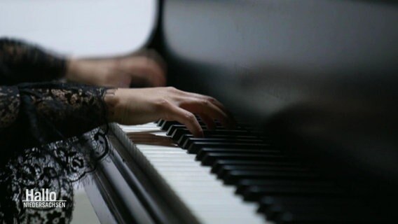 Weibliche Hände, die auf der Klaviatur eines Flügels spielen. © Screenshot 