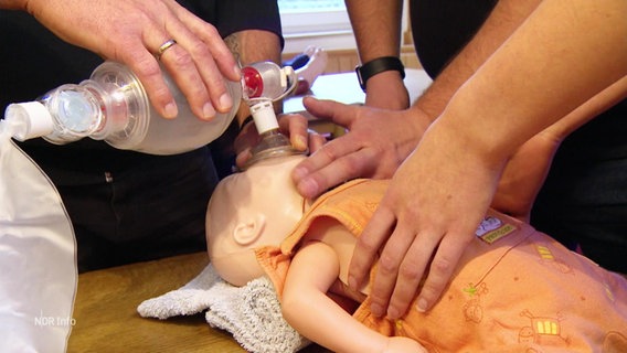 Mit einer Puppe wird die Reanimation eines Kleinkindes geübt. © Screenshot 