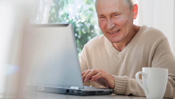 Russlands Präsident Putin lächelnd vor einem Laptop. © NDR 