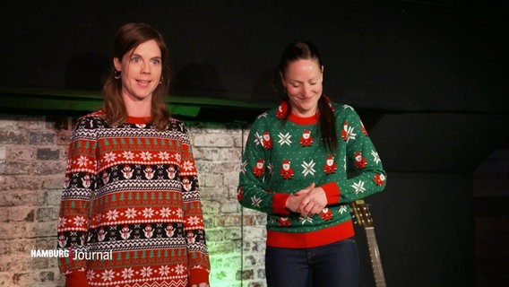 Zwei Frauen in Weihnachtsklamotten stehen auf einer Bühne. © Screenshot 