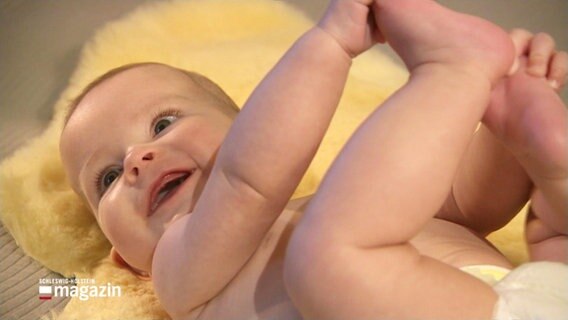 Ein lachendes Baby liegt auf dem Rücken. © Screenshot 