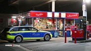 Ein Polizeiauto steht vor einer Tankstelle. © Screenshot 
