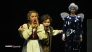 Szene aus der Oper "Hänsel und Gretel": Hänsel und Gretel singen aufgeregt. Im Hintergrund steht die böse Stiefmutter. © Screenshot 
