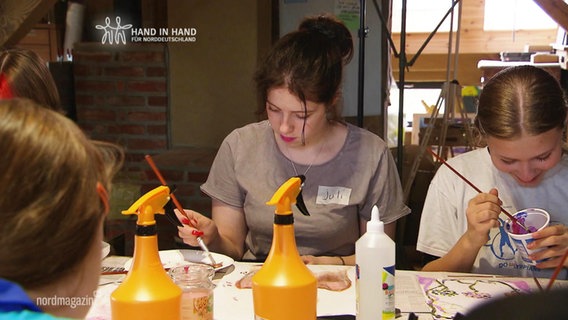 Kinder und Jugendliche malen an einem Tisch. © Screenshot 