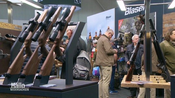 An einem messestand stehen mehrere Jagdgewehre aufgereiht. © Screenshot 