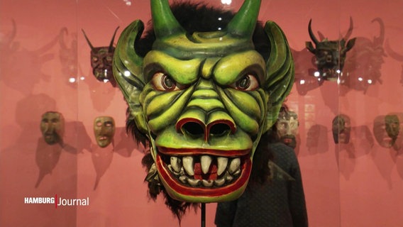 Eine grüne Maske in einer Ausstellung. © Screenshot 