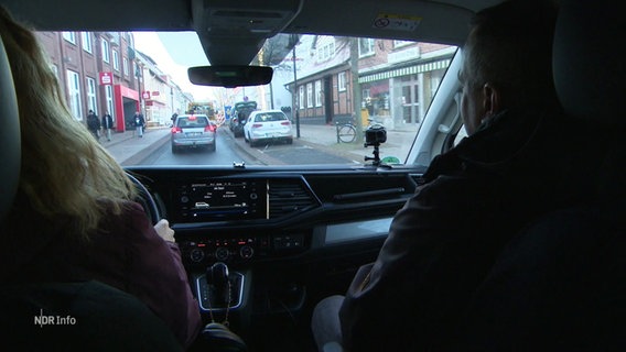 Fahlehrer und Schülerin im Cockpit eines Autos während einer Fahrstunde. © Screenshot 