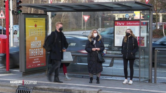 Menschen mit Maske warten an einer Bushaltestelle. © Screenshot 