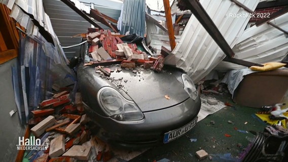 Ein Sportwagen ist unter Bauschutt und Ziegelsteinen einer eingestürzten Garage begraben. © Screenshot 