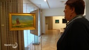 Eine Frau steht in einem Museum und betrachtet ein Bild. © Screenshot 