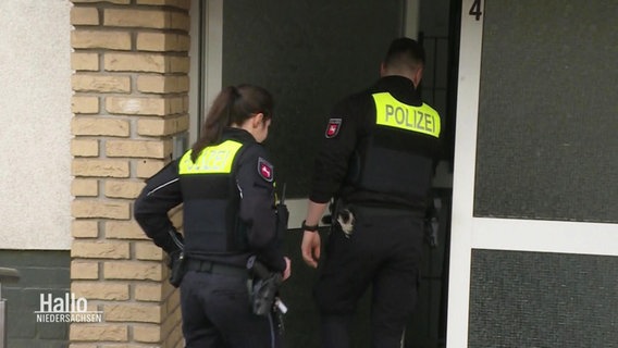 Zwei Polizeibeamte betreten ein Wohnhaus. © Screenshot 