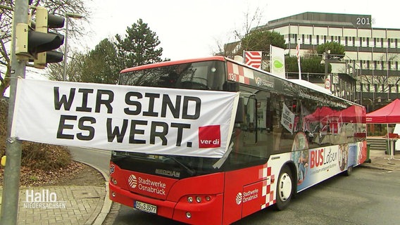 Ein Banner vor einem Bus mit der Aufschrift:" Wir Sind Es Wert" © Screenshot 