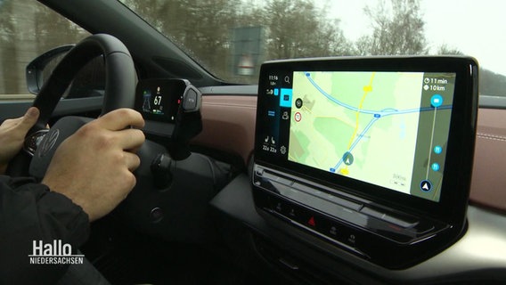 In einem modernen Auto sieht man zwei Hände die das Lenkrad halten sowie den Bildschirm des Boardcomputers mit Navigationsprogramm. © Screenshot 