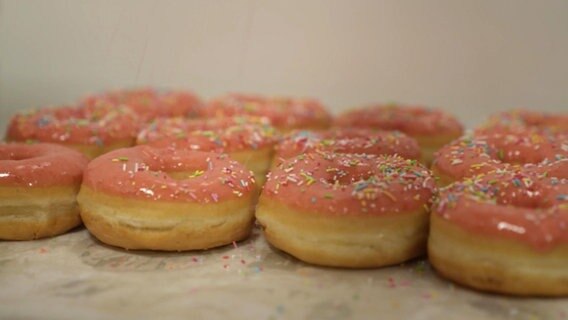 Donuts mit Zuckerstreuseln liegen nebeneinander auf einem Blech. © Screenshot 
