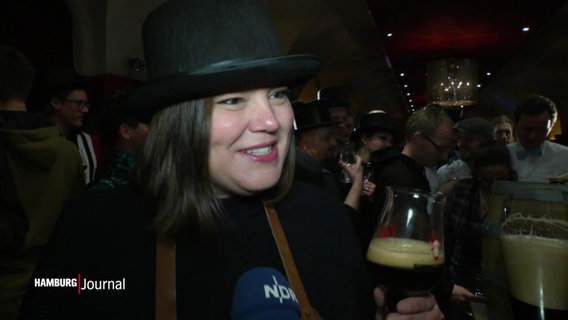 Katharine Fegebank im Interview, sie trägt einen schwarzen Hut und hält ein Bier in der Hand. © Screenshot 