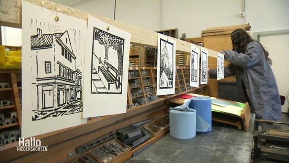 Mehrere Drucke hängen zum Trocknen in einer Werkstatt. © Screenshot 