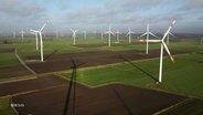 Blick aus hoher Höhe: Über einen weites Landstück stehen mehrere Windkrafträder auf Feldern. © Screenshot 