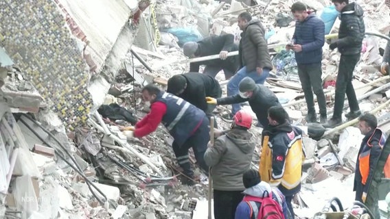 In den trümmern eines durch ein Erdbeben eingestürzten Gebäudes suchen mehrere Menschen nach Überlebenden. © Screenshot 