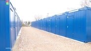 Blaue Container die in zwei langen Reihen aufgestellt sind © Screenshot 