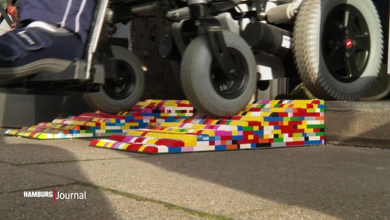 Ein Rollstuhl fährt über eine Rampe aus Legosteinen. © Screenshot 