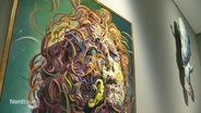 Kunstwerk von Glenn Brown in einer Ausstellung: Ein Kopf, vollkommen umwirbelt von farbigen Locken, vor einem grünen Hintergrund © Screenshot 