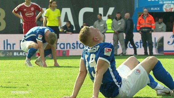 Enttäuschte Spieler von Hansa Rostock sitzen auf dem Rasen. © Screenshot 