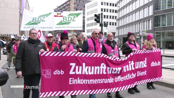 Die Streikenden mit Transparenetn und Fahnen in einem Demonstrationszug © Screenshot 