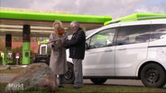 Zwei Personen an einer Tankstelle vor einem Auto © Screenshot 