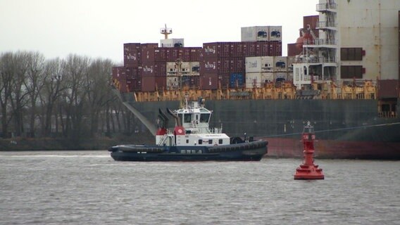 Ein Lotsenboot neben einem großen Containerschiff auf der Elbe. © Screenshot 