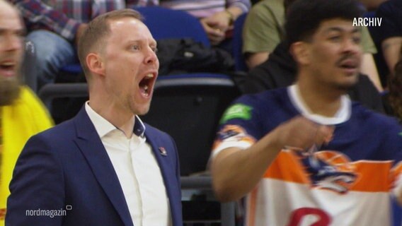 Trainer Christian Held steht bei einem Basketballspiel am Spielfeldrand und schreit. © Screenshot 