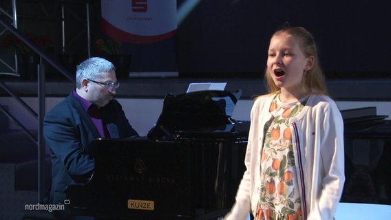 Ein Pianist und ein singendes Mädchen auf einer Bühne © Screenshot 