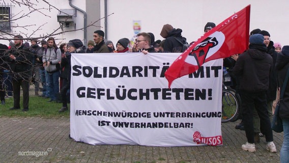 Demonstrierende Menschen halten ein Banner mit der Aufschrift:"Solidarität mit Geflüchteten!" © Screenshot 