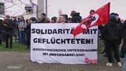 Demonstrierende Menschen halten ein Banner mit der Aufschrift:"Solidarität mit Geflüchteten!" © Screenshot 