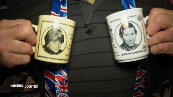 Nahaufnahme von zwei mit König Charles und Prinzessin Diana's Gesicht bedruckten Tassen. © Screenshot 